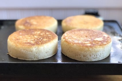 Sourdough crumpets baking on a griddle